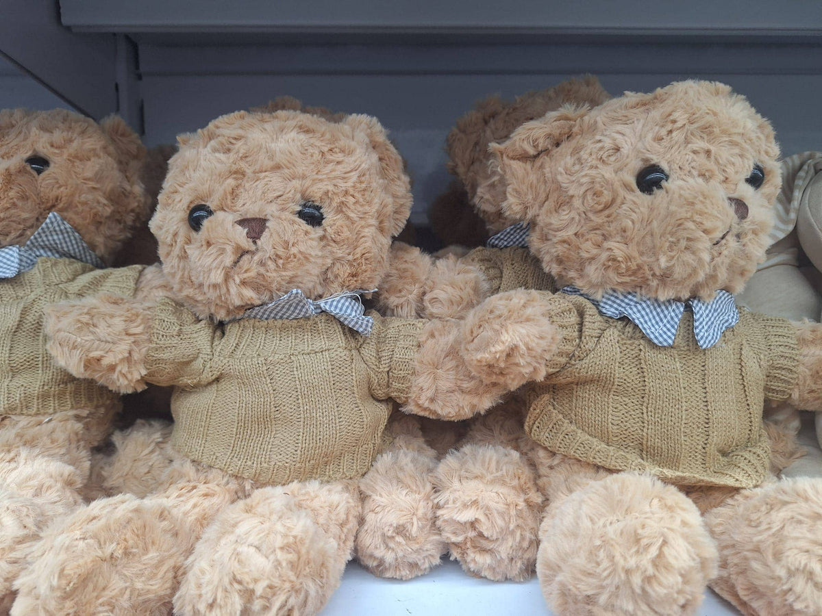 Soft teddy bear wearing a camel cable-knit jumper with a light blue collar