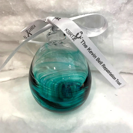 Close-up of a Green hand-blown glass Christmas bauble tied with the Kevin Bell Repatriation Trust ribbon