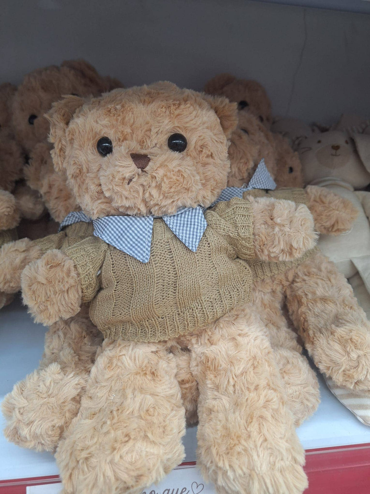 Soft teddy bear wearing a camel cable-knit jumper with a light blue collar