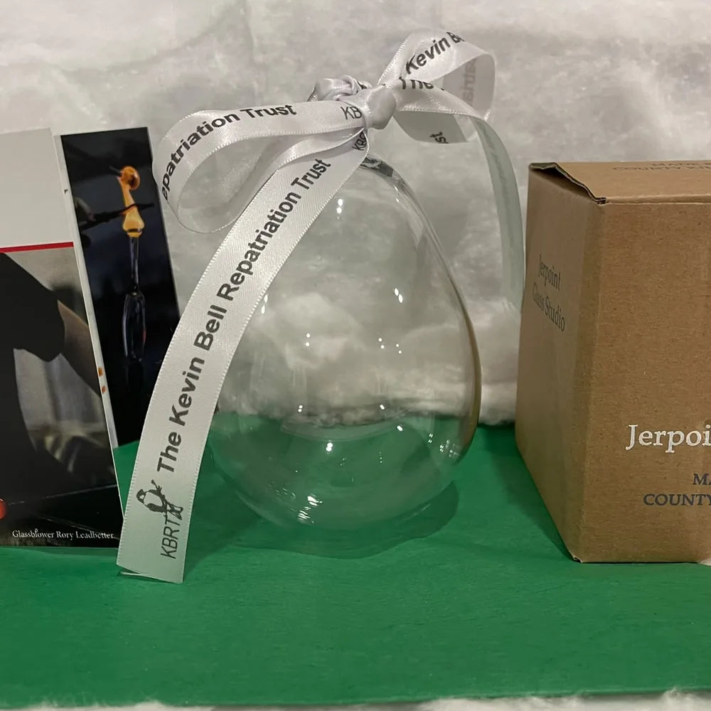 Clear hand-blown glass bauble with the Kevin Bell Repatriation Trust ribbon, beside its story card and gift box